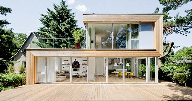 Bild Haus Jacobs. Holzbau mit großen Fensterfronten und Staffelgeschoss mit Dachterrasse. Im Vordergrund: Holzterrasse.