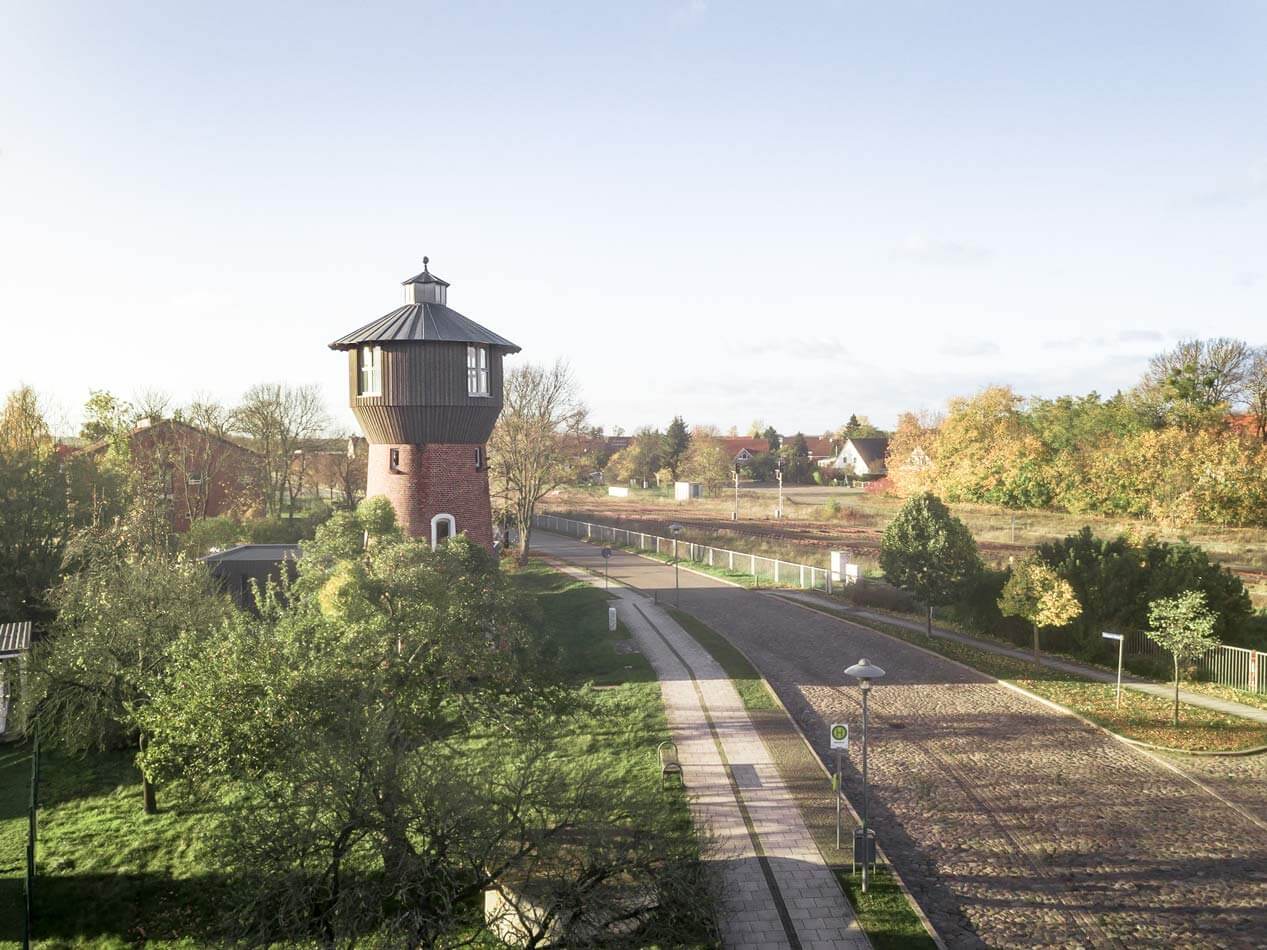 Bild vom Wasserturm in Löcknitz. Blick auf den Tür welcher unten aus Mauerwerk und am Kopf mit Holz verschalt ist. Auf der rechten Seite des Bildes sieht man die Straße.
