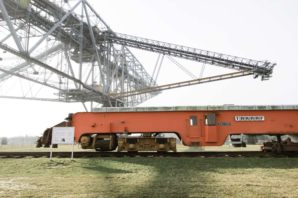 Förderbrücke F60 mit einem rot-orange farbenen Fördermittel im ehemaligen Tagebau am Bergheider See.