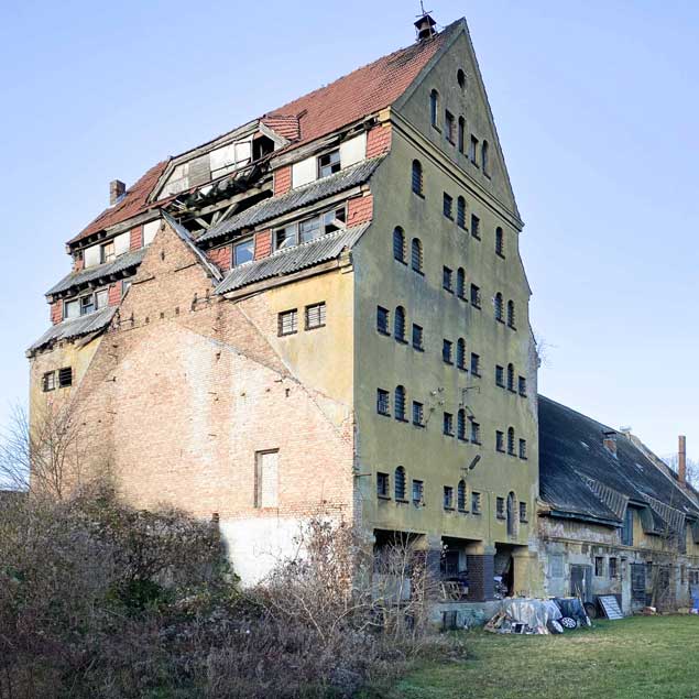 Rügenspeicher: Ehemaliger Speicher im unsanierten Zustand. Die Fassade bröckelt nach mehr als 30 Jahren Leerstand. Ein Teil des Stallgebäudes ist abgebrochen, da der Zustand marode war.