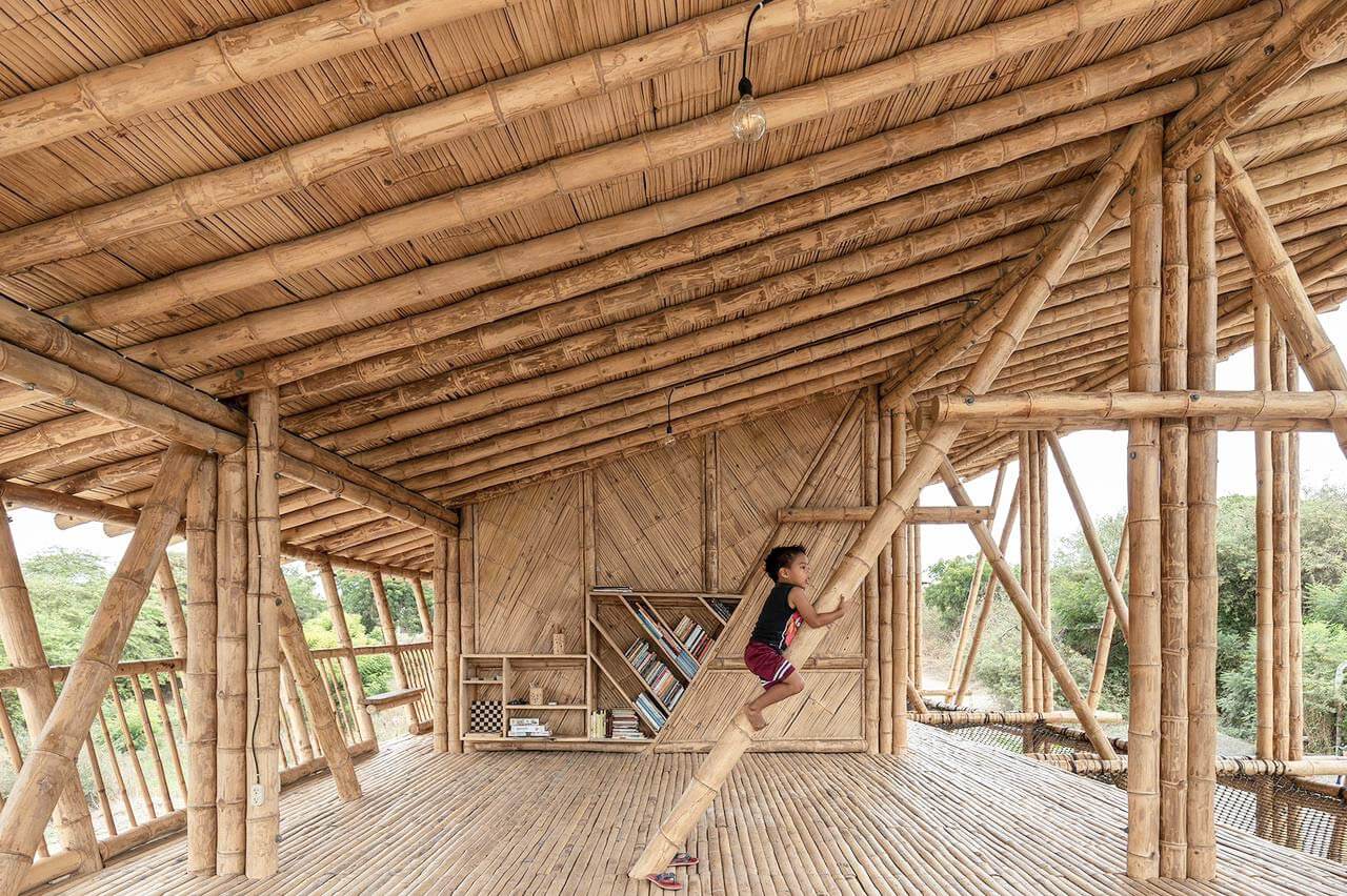 Bild vom Innenbereich des Gemeindezentrums Las Gilces. Das Gebäude und der Innenraum wurden komplett aus Bambus gefertigt. Man sieht in der Mitte des Bildes einen kleinen Jungen der an einem Bambusstab hochklettert.
