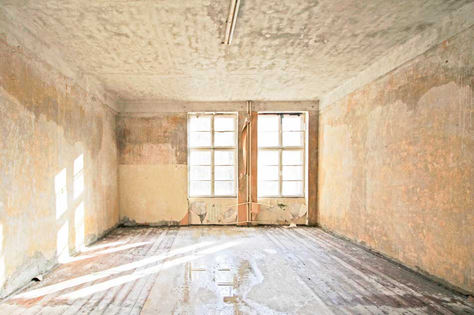 Innrenraumansicht der ehemaligen Infanterieschule Wünsdorf in weißem und ockerfarbenem, abbläterndem Putz, Wasser auf dem Boden.