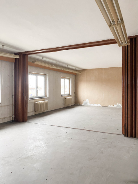 BAHN5-1_cubus-plan Innenraumansicht vor dem Umbau und der Renovierung mit Zieharmonikawand in geöffnetem Zustand, abgeplatzter Farbe und Neonleuchten an der Decke.Innenraumansicht vor dem Umbau und der Renovierung mit Zieharmonikawand in geöffnetem Zustand.