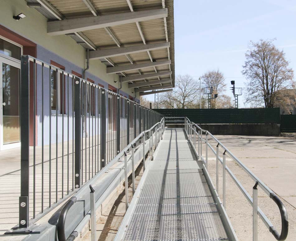 BAHN5-10-950_cubus-plan Angeschnittene Ansicht des EFJ-Wohngebäudes mit zweifarbiger Zonierung, unten sanftes Blaugrau oben helles Grün. Rollstuhlzugang, barrierefreier Eingang des Umbaus mit Vordach.