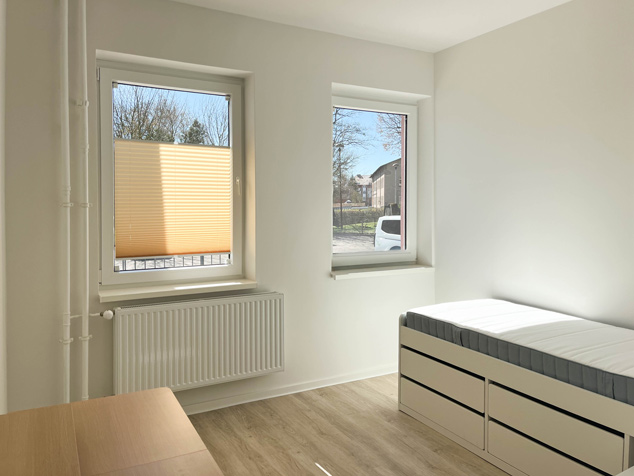 BAHN5-14_cubus-plan Innenraumansicht eines Schlaf- / Kinderzimmers mit Bett und Tisch mit Blick nach draußen.