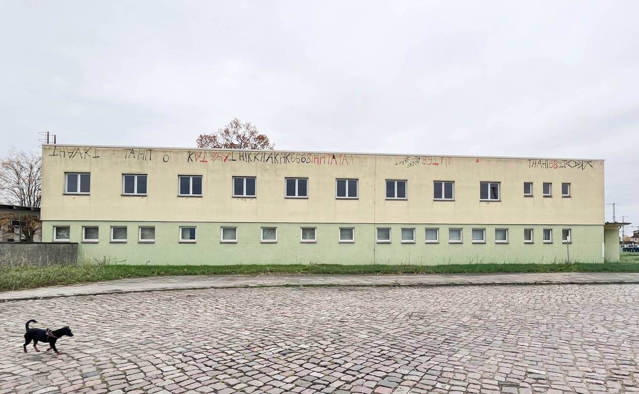 bahn5-15_vorher_cubus-plan Die Rückseite des Gebäudes vor dem Umbau mit gelb-grüner Farbe und Graffiti im oberen Fassadenbereich.