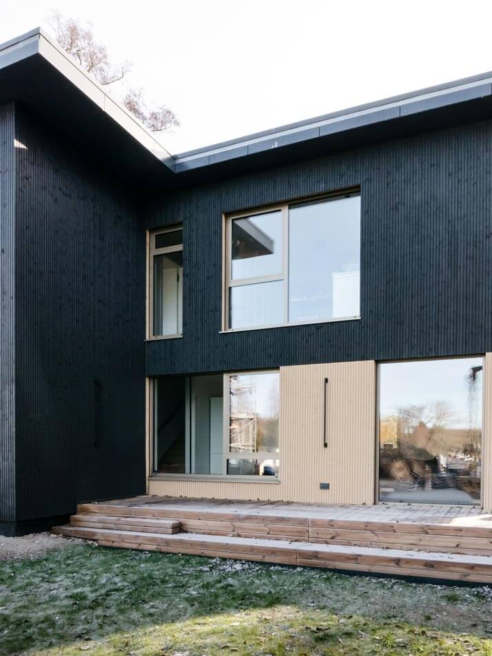 Nahansicht des zweifarbigen Gebäudes, oben in dunklem, unten in hellem Holz.